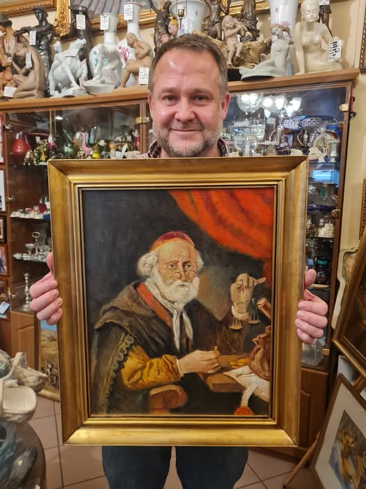 Egy ember festményt tart a kezében.